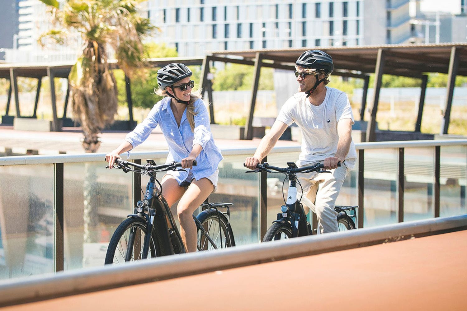 Couple riding two Merida electric hybrid bikes down wharf