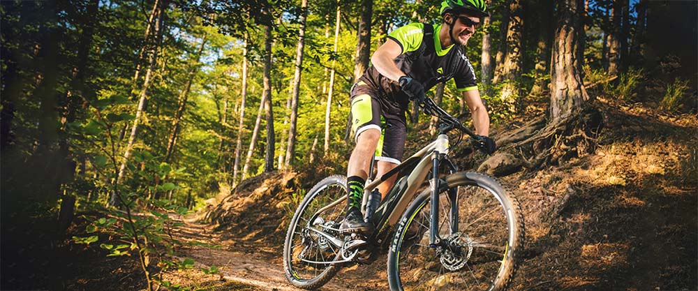 Cyclist riding down hill on electric hybrid mountain bike