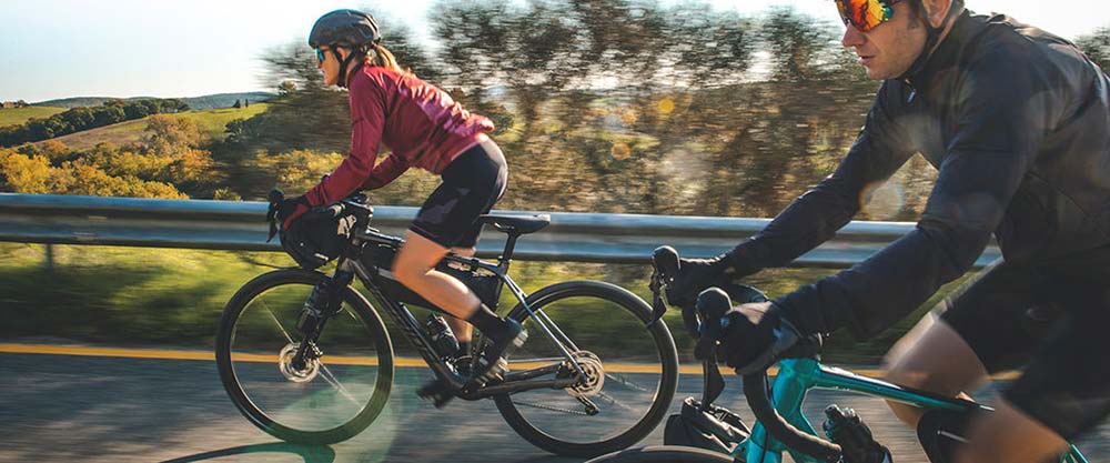 Couple riding uphill on two electric gravel bikes