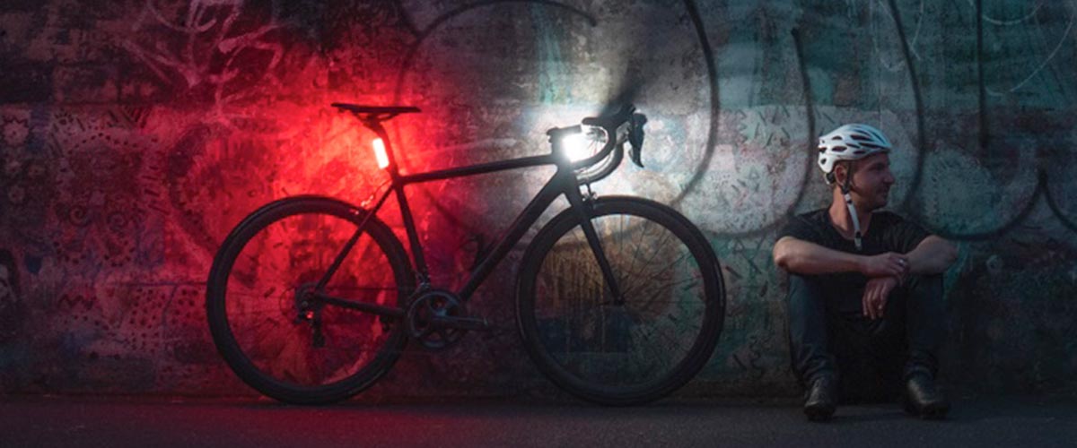 Cyclist sitting next to bike with front and rear light on