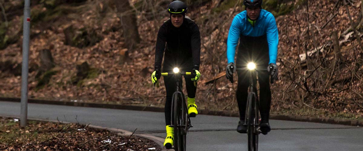 Two cyclist riding with front lights on