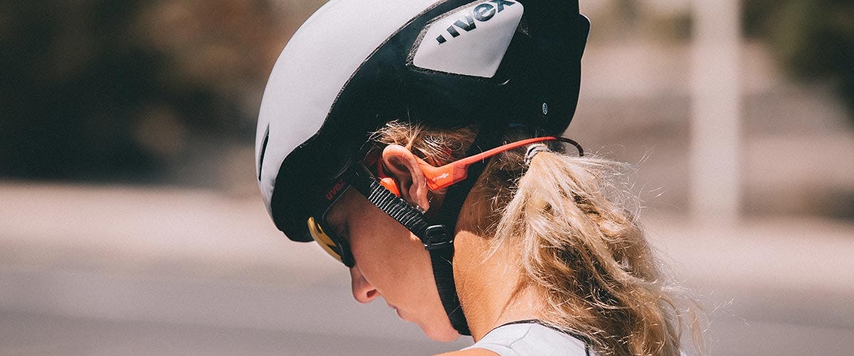 Cyclist riding bike with Aftershokz headphones one