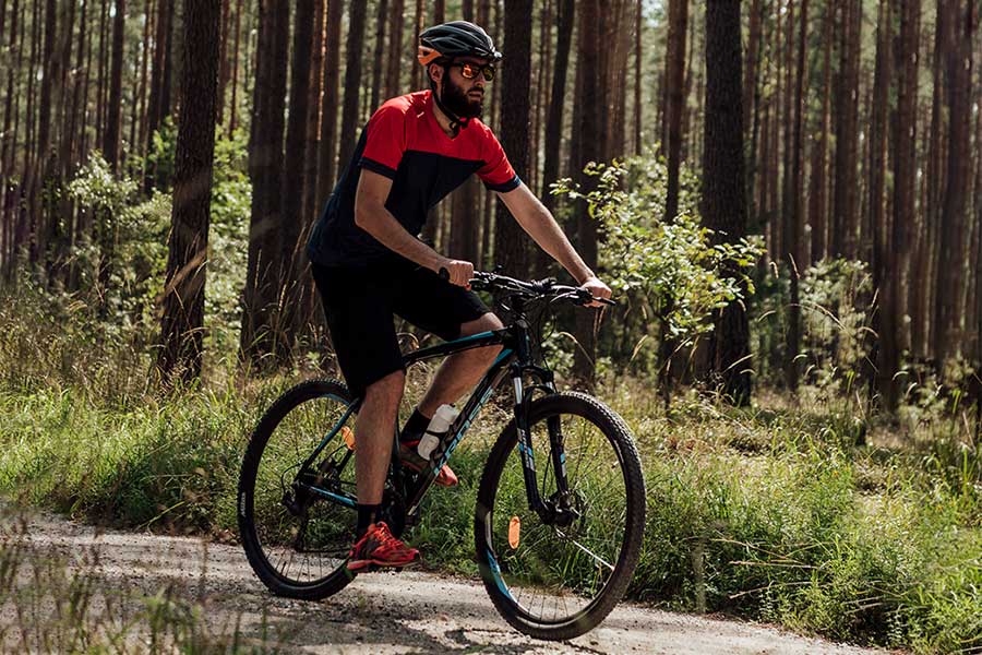 Cyclist riding Kross Hexagon mountain bike along an off-road trail in a bush