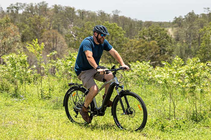 Man riding Merida electric commuting bike off-road up grassy hill